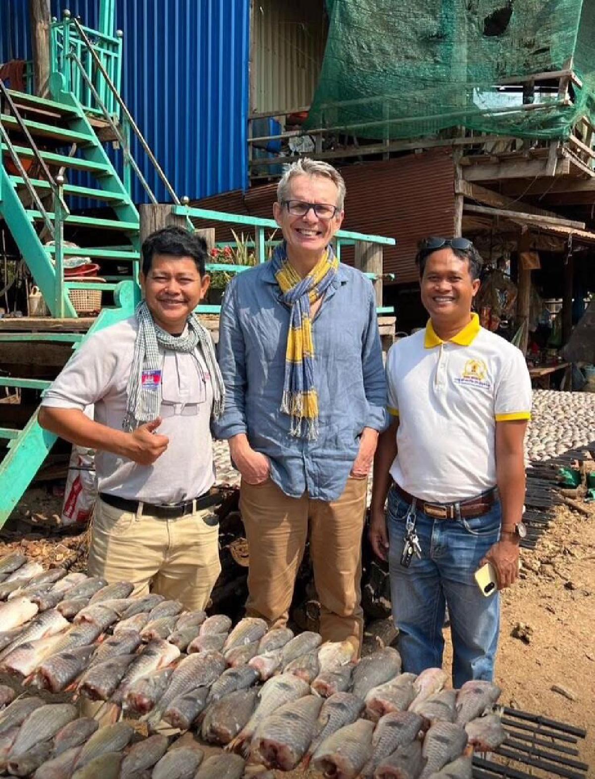 A guest with two local partners at a lakeside fish market