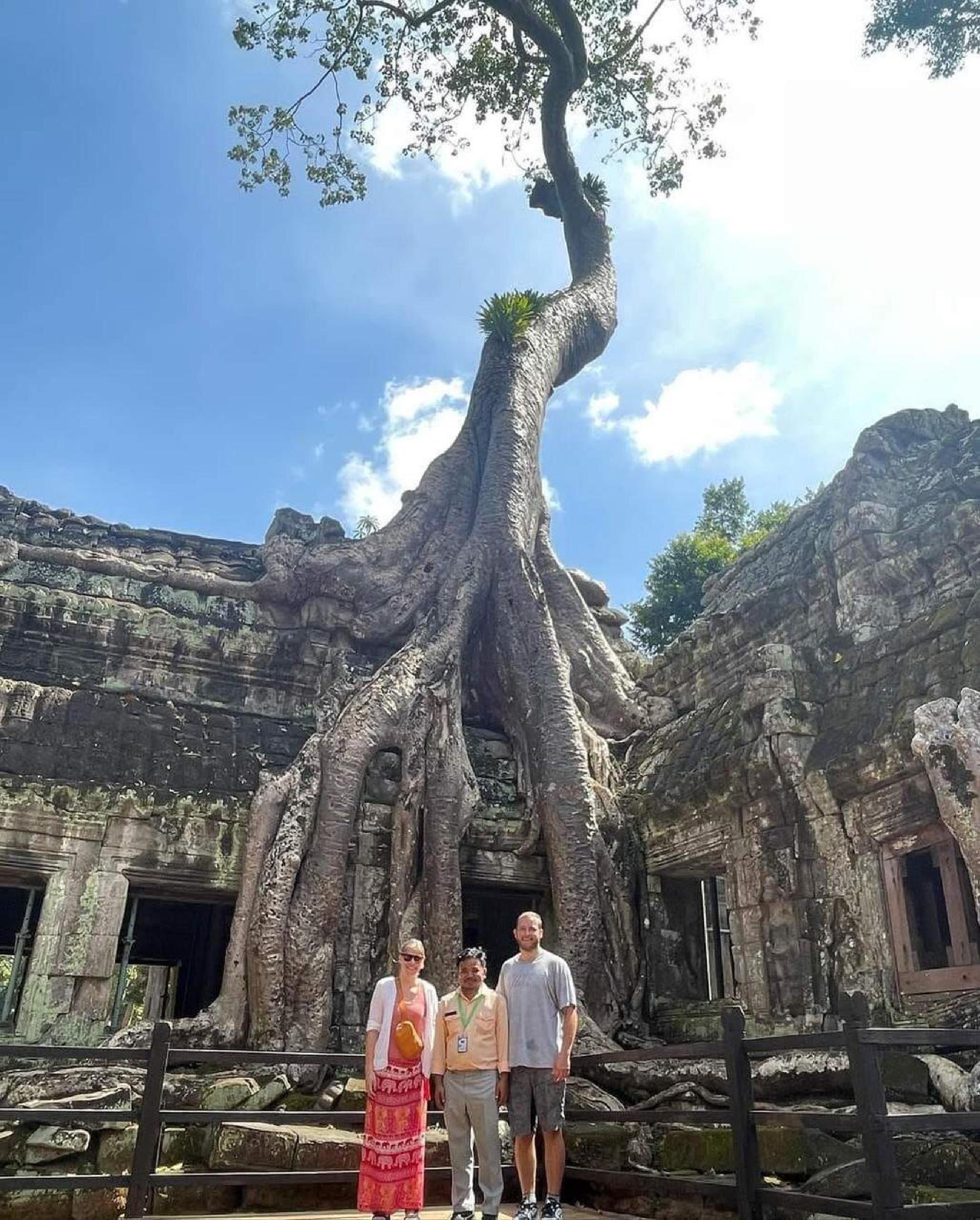 Guests beneath the giant tree roots at Ta Prohm temple